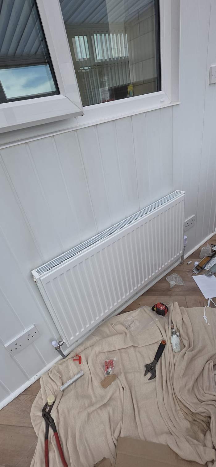 New radiator installed under a window in a garden room