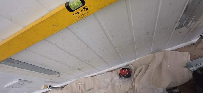 Spirit level checking a wall before radiator brackets go up