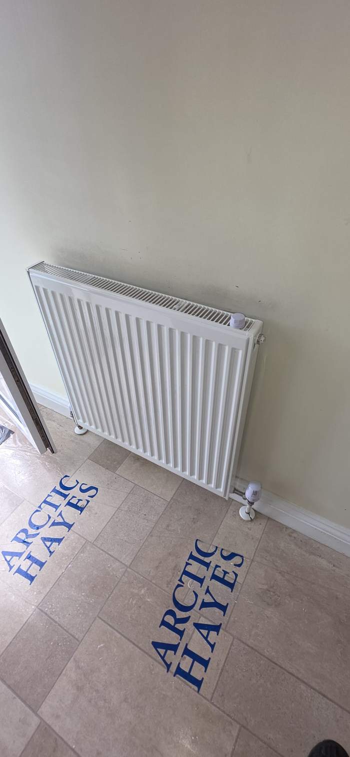 Replacement radiator fitted in a tiled hallway