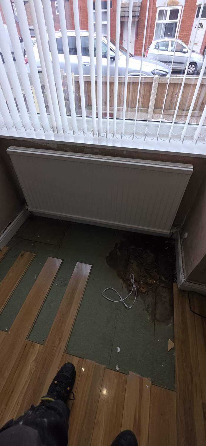 Flooring lifted beneath a radiator to trace a leak